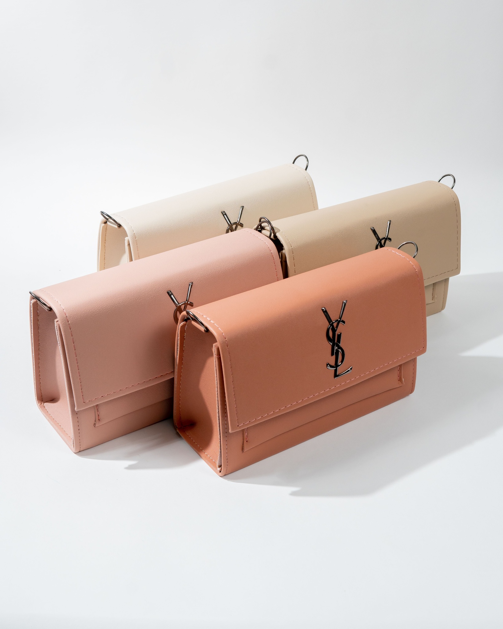 Soft pink and beige handbags arranged on a white surface