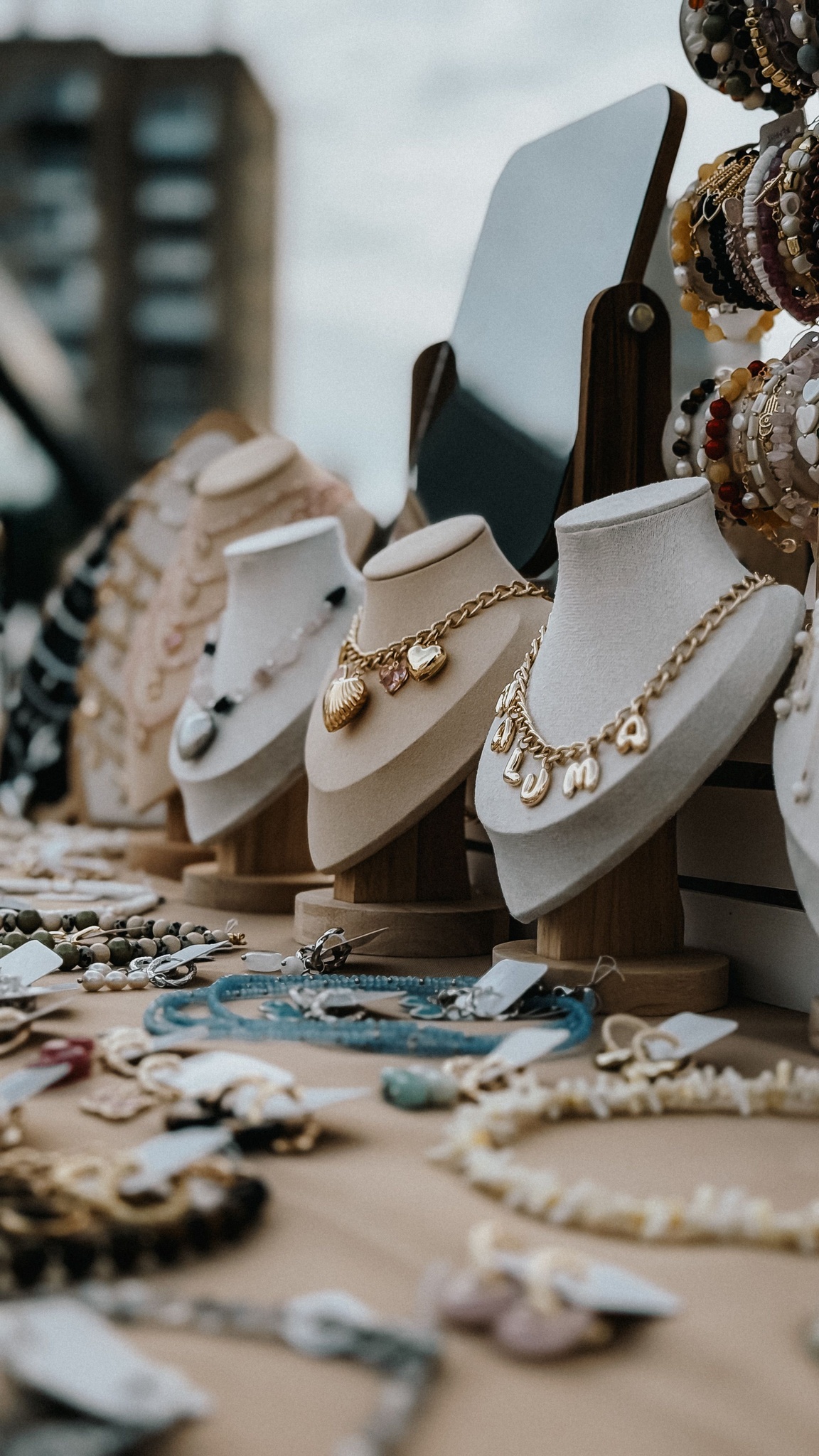 Necklaces displayed on stands and busts in warm afternoon light