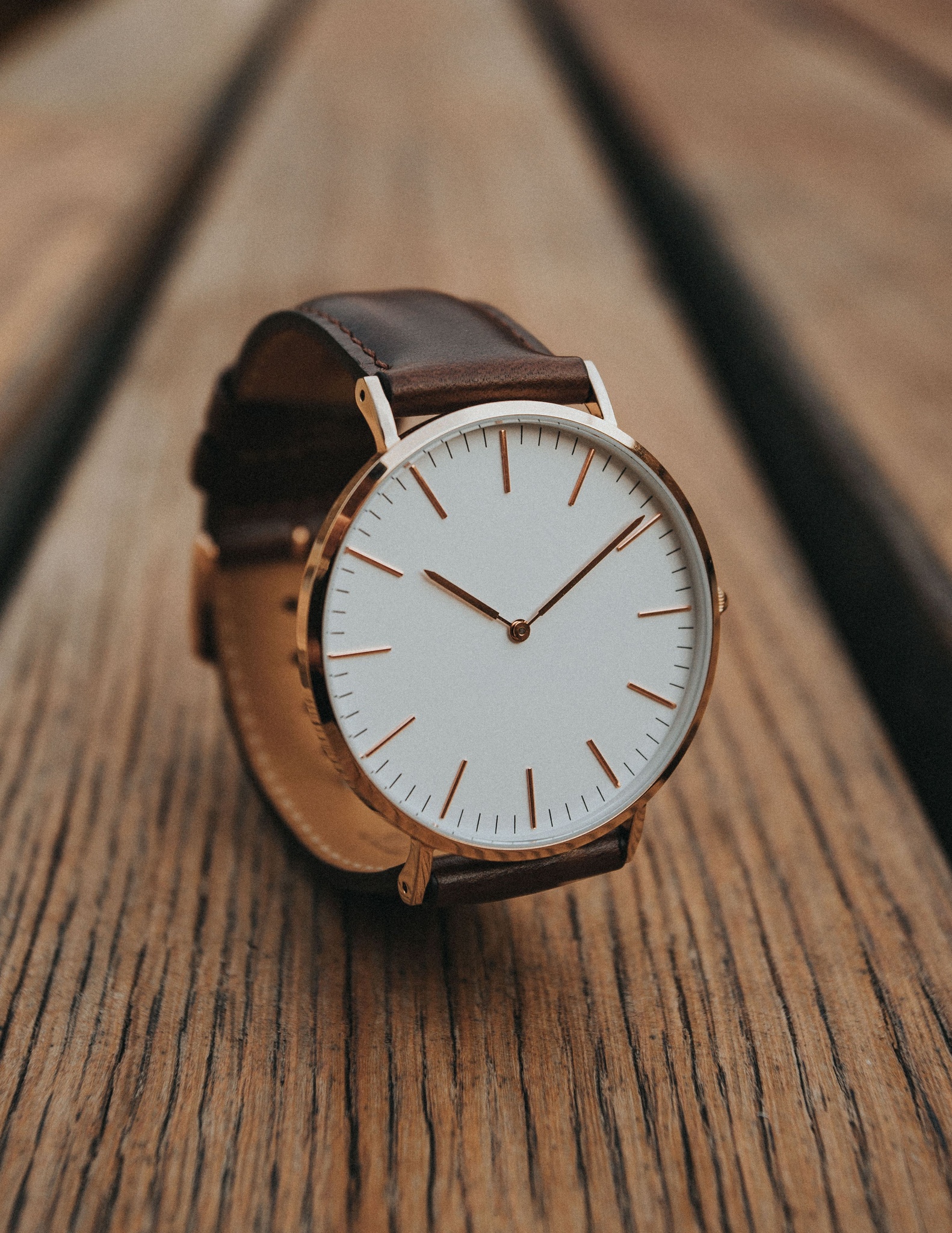 Rose gold watch with a white dial and a brown leather strap