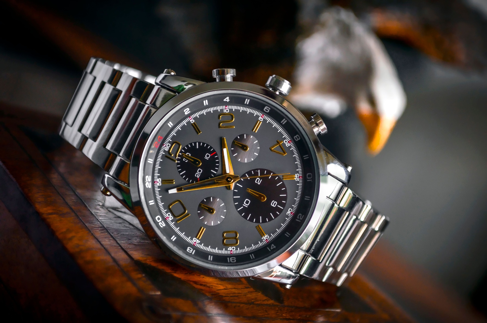 Silver chronograph watch with a grey dial on a dark wooden surface